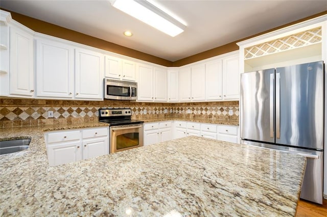 kitchen featuring white cabinets, light stone counters, and stainless steel appliances