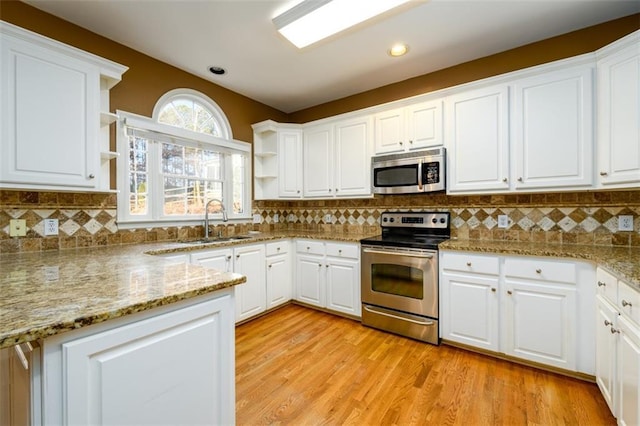 kitchen featuring backsplash, sink, appliances with stainless steel finishes, light stone counters, and white cabinetry