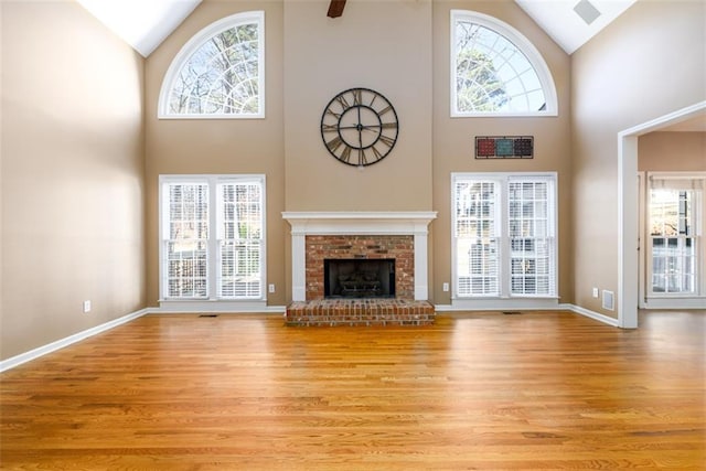 unfurnished living room with a towering ceiling, light hardwood / wood-style floors, and plenty of natural light