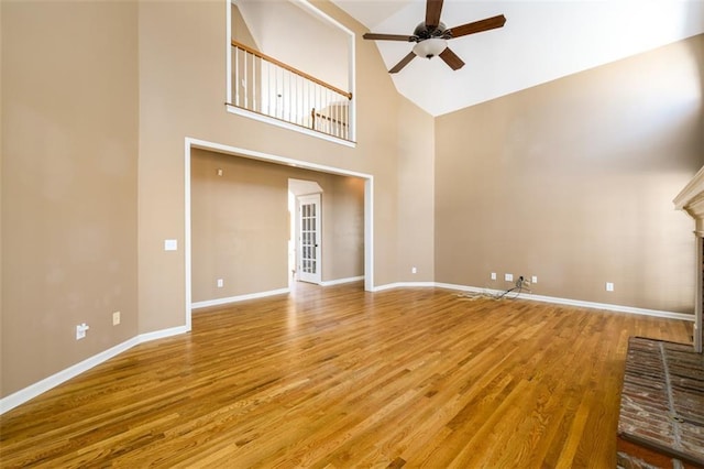 unfurnished living room featuring a high ceiling, ceiling fan, and hardwood / wood-style floors