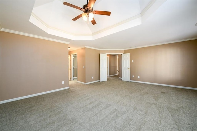 spare room with carpet, ceiling fan, ornamental molding, and a tray ceiling