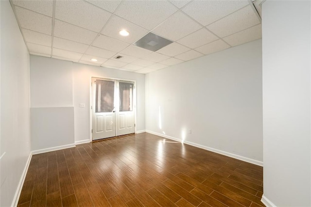 spare room featuring a drop ceiling and dark wood-type flooring