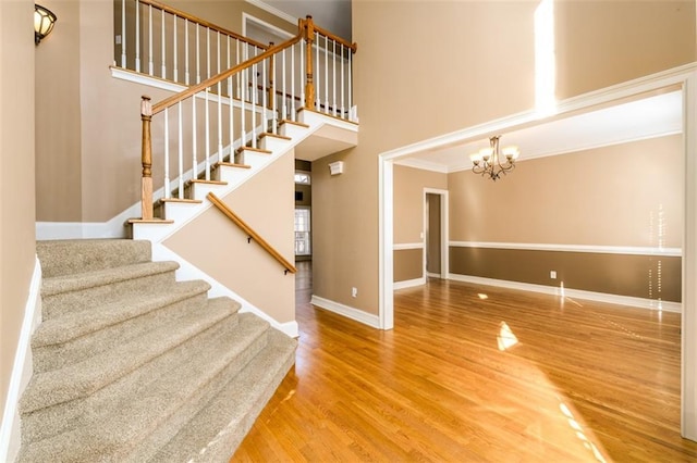 stairway featuring hardwood / wood-style floors, an inviting chandelier, and crown molding