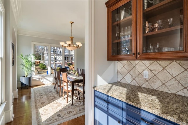 bar with a notable chandelier, hanging light fixtures, backsplash, dark wood-style floors, and crown molding