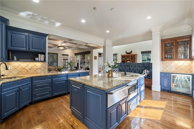 kitchen featuring wine cooler, a sink, a center island with sink, and blue cabinets