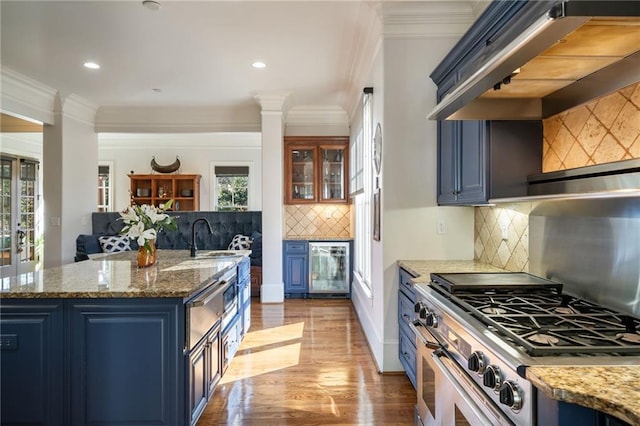 kitchen with wine cooler, range with two ovens, a sink, blue cabinetry, and custom range hood