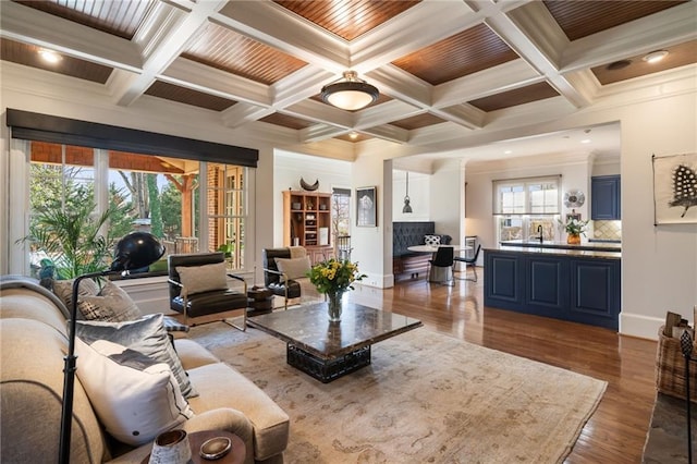 living area with coffered ceiling, beamed ceiling, and wood finished floors