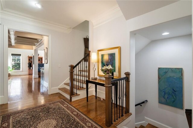 interior space with an AC wall unit, baseboards, wood finished floors, and ornamental molding