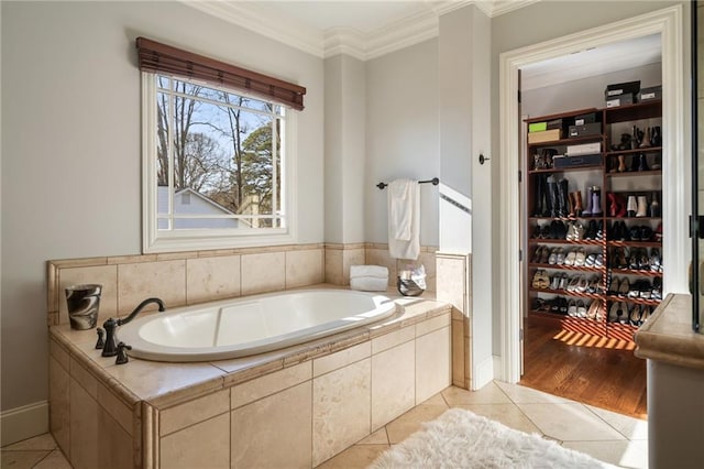 bathroom featuring a garden tub, crown molding, a spacious closet, and tile patterned floors