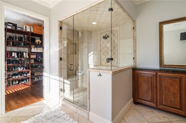 bathroom featuring a stall shower, tile patterned flooring, a walk in closet, and crown molding