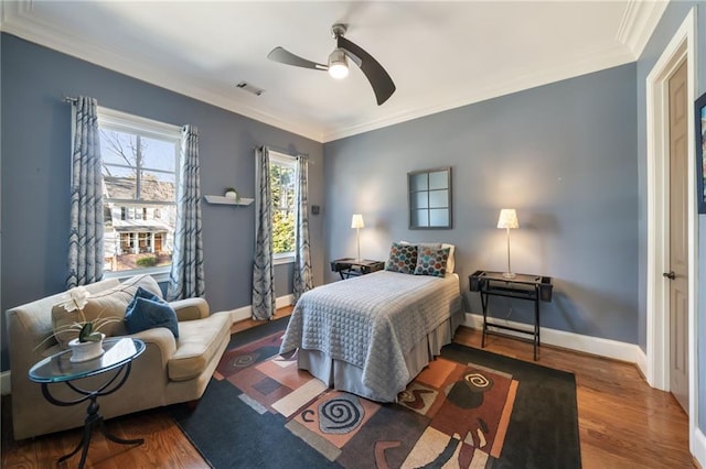 bedroom featuring baseboards, crown molding, visible vents, and wood finished floors