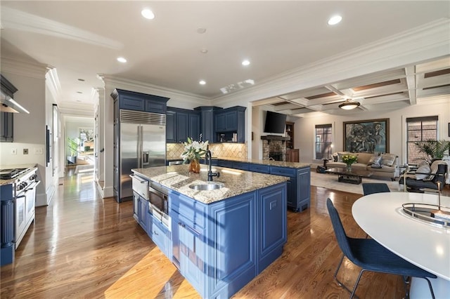 kitchen featuring open floor plan, blue cabinetry, premium appliances, and a sink