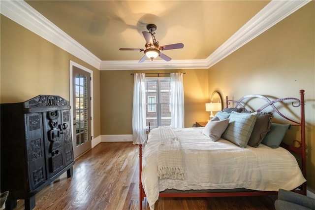 bedroom featuring ornamental molding, multiple windows, and wood finished floors