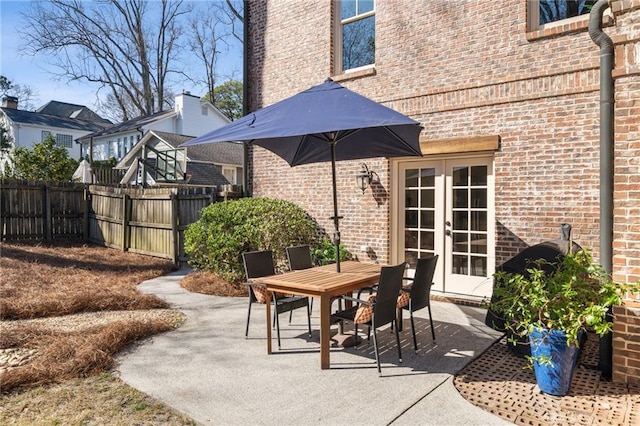 view of patio with french doors, fence, and outdoor dining area