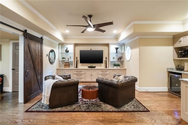 living room featuring ceiling fan, a barn door, light wood-style flooring, baseboards, and crown molding