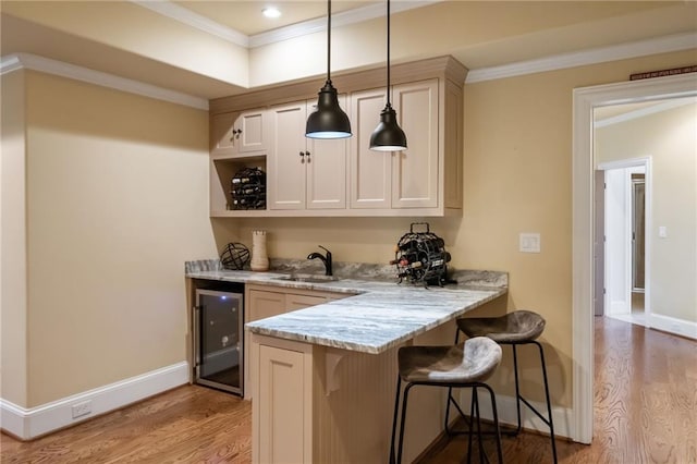 bar with baseboards, wine cooler, crown molding, light wood-style floors, and a sink