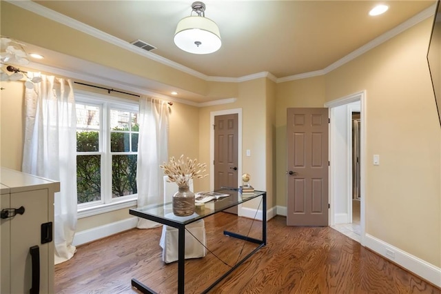 office space with baseboards, crown molding, visible vents, and wood finished floors