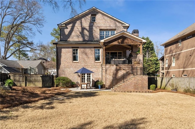 rear view of property featuring brick siding, a patio, a chimney, stairway, and fence