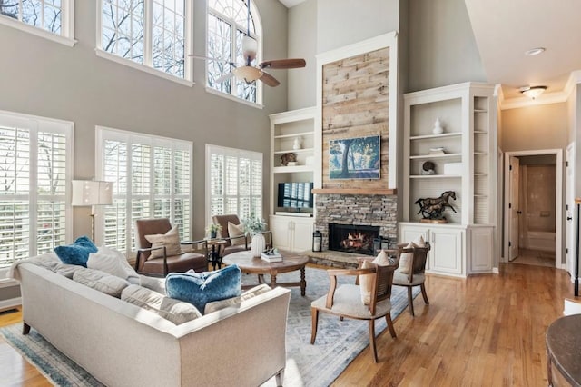 living room with light wood-style flooring, ceiling fan, and a fireplace