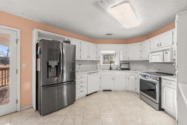 kitchen with a textured ceiling, stainless steel appliances, white cabinetry, and sink