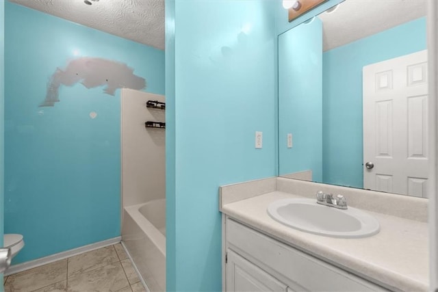 bathroom featuring toilet, vanity, tile patterned flooring, and a textured ceiling