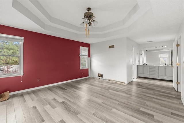 spare room with ceiling fan, light hardwood / wood-style floors, and a tray ceiling