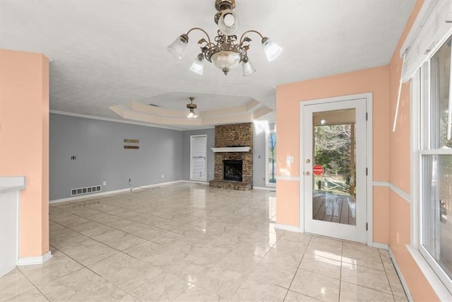 unfurnished living room featuring a fireplace, ceiling fan with notable chandelier, and a tray ceiling