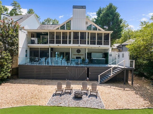 rear view of house with a deck, stairs, a fire pit, a sunroom, and a chimney