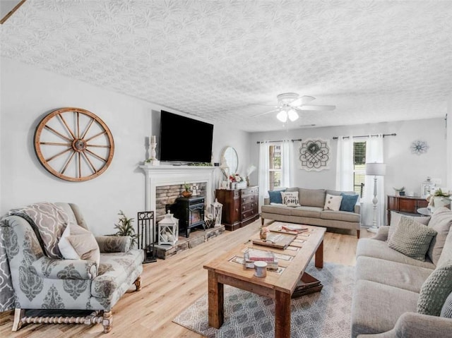 living room featuring a ceiling fan, wood finished floors, and a textured ceiling