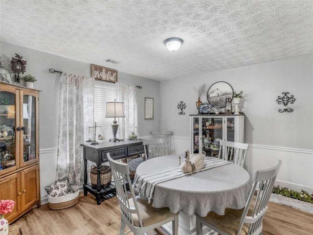 dining room with light wood-style flooring and a textured ceiling