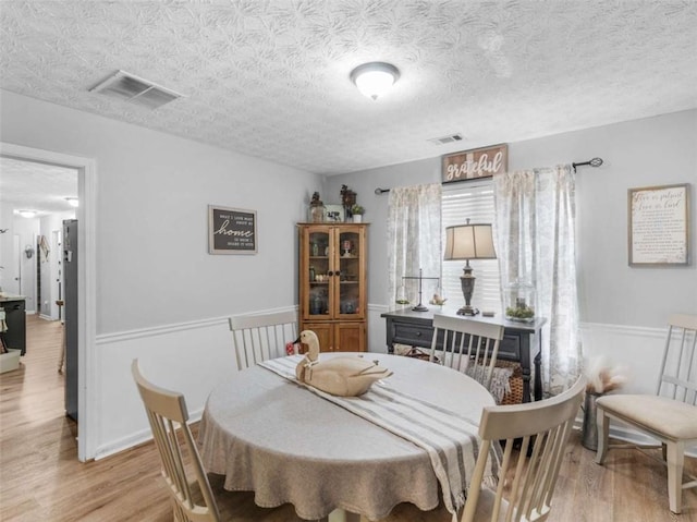 dining room with light wood finished floors and a textured ceiling