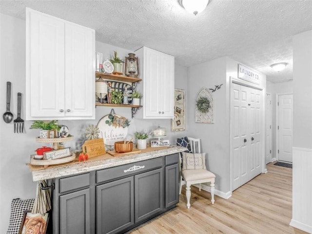 kitchen featuring gray cabinetry, light wood-style floors, open shelves, white cabinets, and a textured ceiling