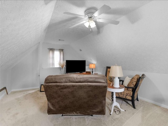 carpeted living area featuring a textured ceiling, vaulted ceiling, baseboards, and ceiling fan
