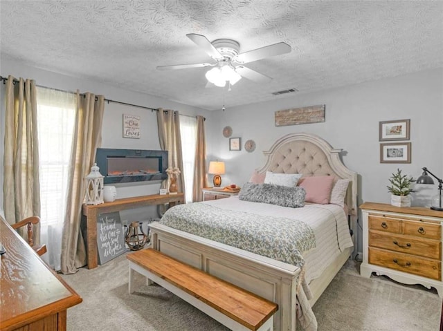 bedroom featuring light carpet, a textured ceiling, and ceiling fan