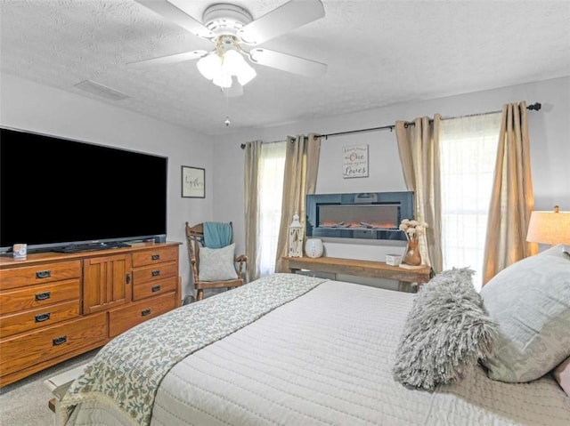 carpeted bedroom with a textured ceiling and a ceiling fan