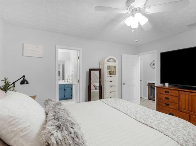 bedroom featuring ensuite bath, ceiling fan, and a textured ceiling