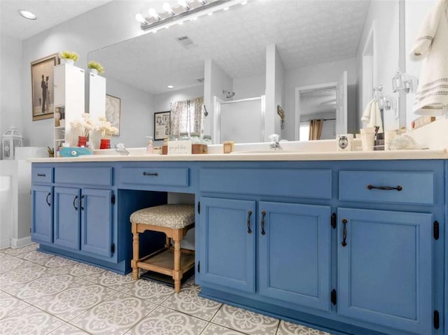 full bathroom featuring a stall shower, tile patterned floors, a textured ceiling, and vanity