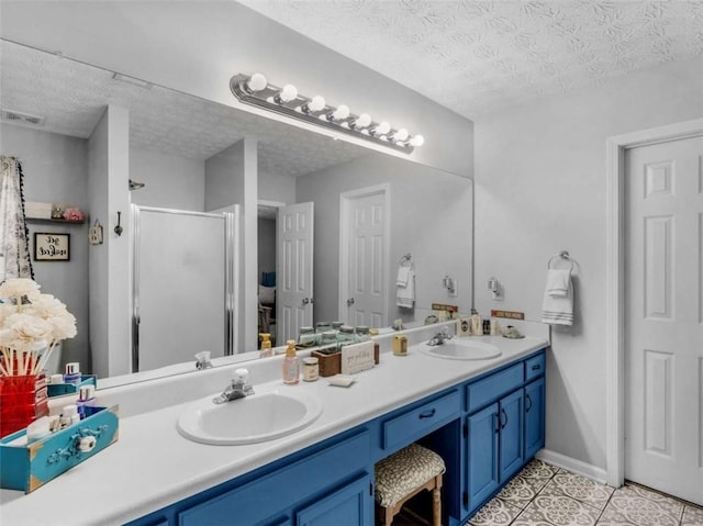 full bathroom featuring a textured ceiling, a stall shower, double vanity, and tile patterned flooring