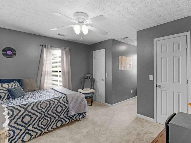 bedroom with ceiling fan, light carpet, a textured ceiling, and baseboards