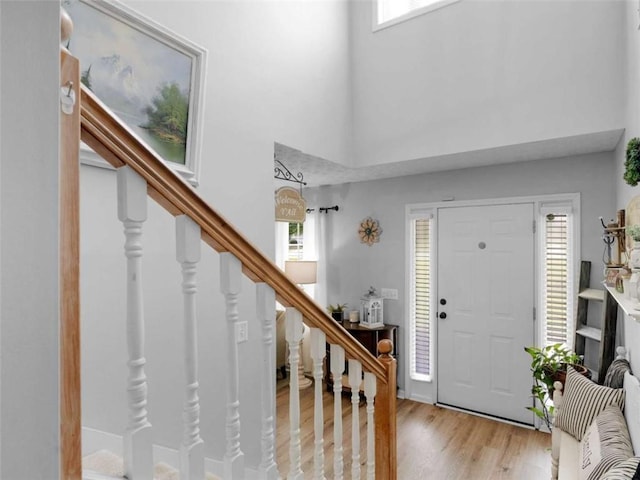 foyer with healthy amount of natural light, stairs, a towering ceiling, and wood finished floors