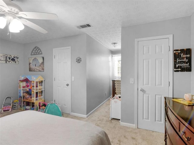 bedroom featuring light carpet, baseboards, a textured ceiling, and a ceiling fan