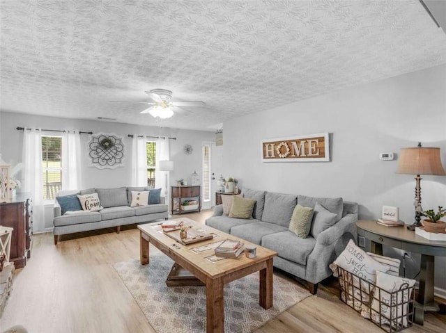 living area with wood finished floors, a ceiling fan, and a textured ceiling