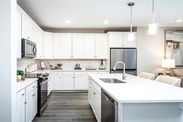 kitchen with stainless steel appliances, white cabinets, dark hardwood / wood-style floors, backsplash, and a kitchen island with sink