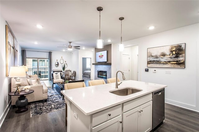 kitchen with dark hardwood / wood-style floors, a fireplace, dishwasher, and an island with sink