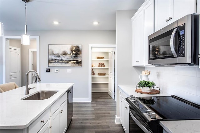 kitchen featuring sink, appliances with stainless steel finishes, pendant lighting, a kitchen island with sink, and white cabinets