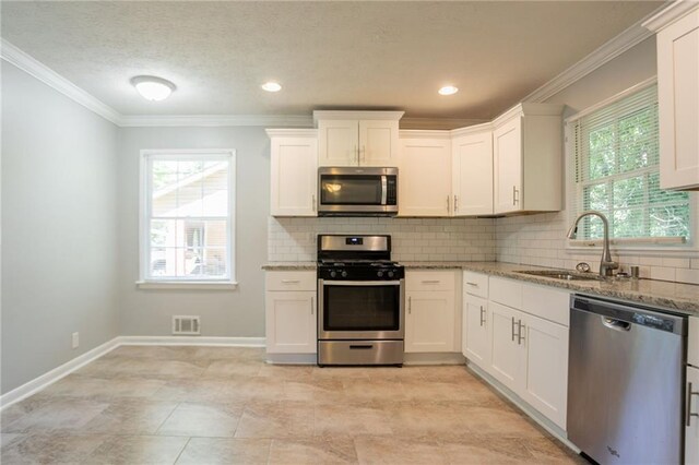 802 San Miguel Dr, Stone Mountain, GA 30083 - kitchen featuring stainless steel appliances, a sink, healthy amount of natural light, light stone counters, and crown molding