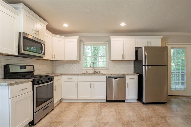 802 San Miguel Dr, Stone Mountain, GA 30083 - kitchen with appliances with stainless steel finishes, a sink, ornamental molding, white cabinets, and light stone countertops