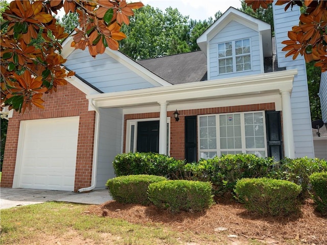 view of front of home with driveway, a shingled roof, an attached garage, and brick siding