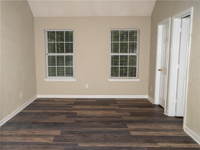 spare room with lofted ceiling, dark wood-style flooring, and baseboards