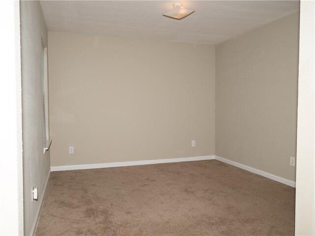 spare room featuring light carpet and baseboards